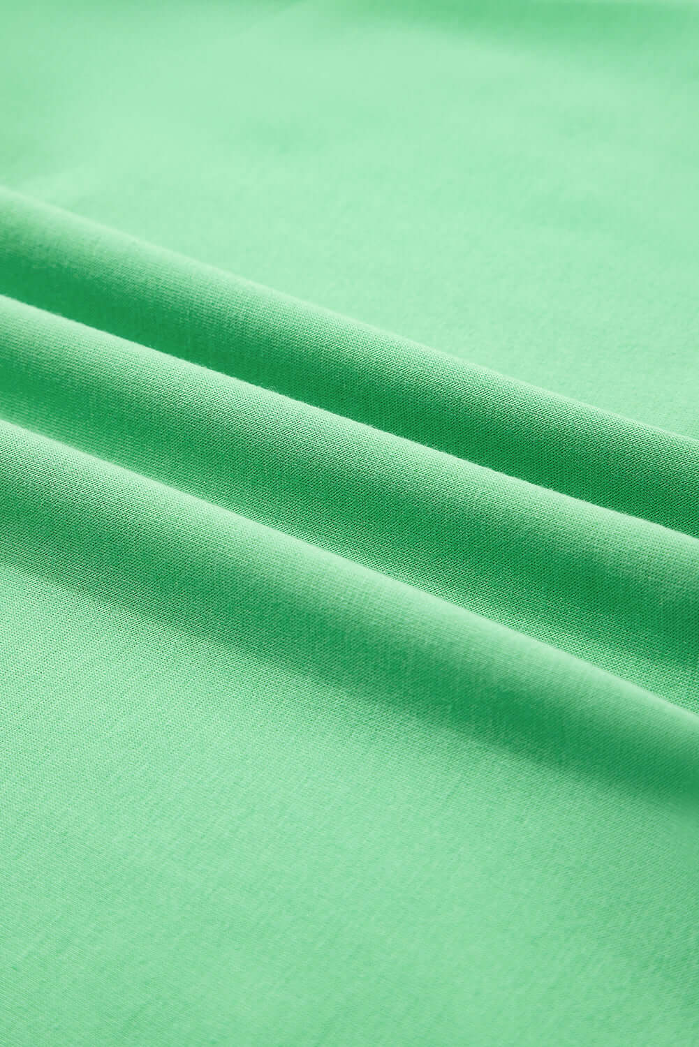 Bright green fabric showcasing a smooth texture, perfect for warm-weather clothing like the Zest for Life shorts set.
