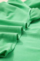 Close-up of vibrant green fabric showcasing the relaxed fit of a V-neck tee from the Zest for Life shorts set.