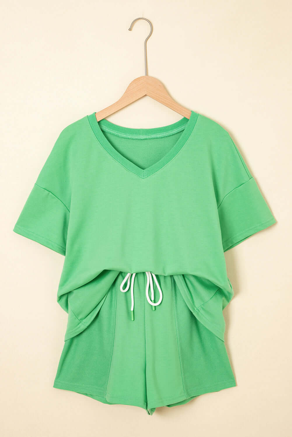 Zest for Life bright green shorts set with V-neck tee and adjustable drawstring shorts hanging on a wall.