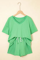 Zest for Life bright green shorts set with V-neck tee and adjustable drawstring shorts hanging on a wall.