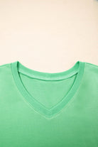 Close-up of a bright green V-neck tee collar from the Zest for Life shorts set on a light background.