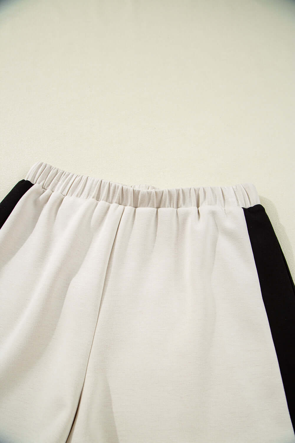 Close-up of the elastic waistband and side slits of Monochrome Motion Shorts Set in black and cream colorblock design.