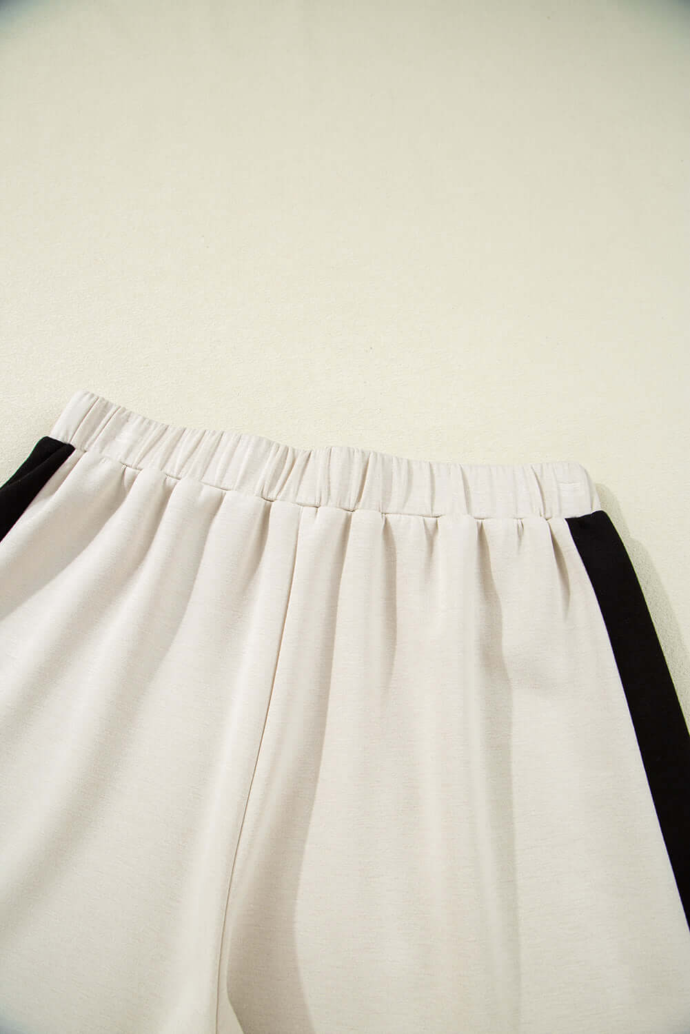 Elastic waist shorts with black and cream colorblock design for sporty chic style.