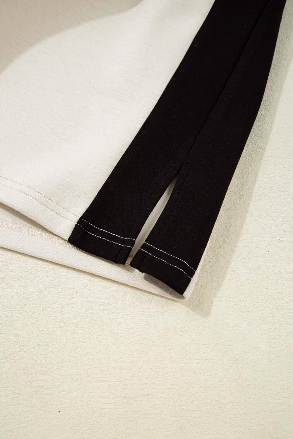 Close-up of the black and cream colorblock design with side slits from the METRO MODE Shorts Set.