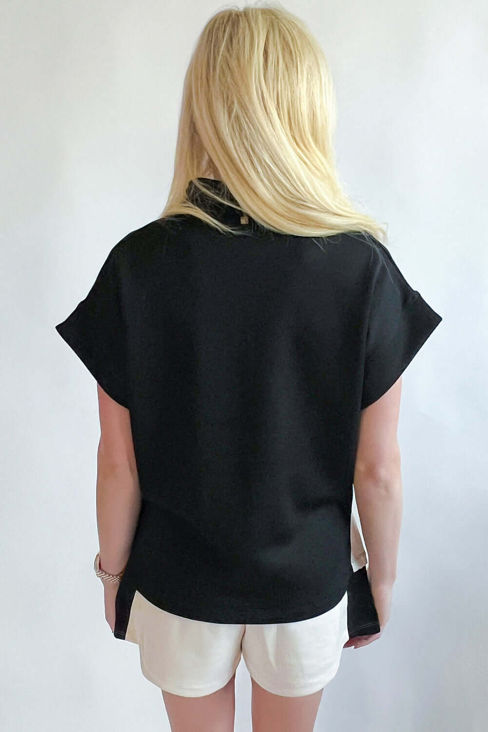 Back view of the Monochrome Motion Zip Collar 2-piece set featuring black top and cream shorts.