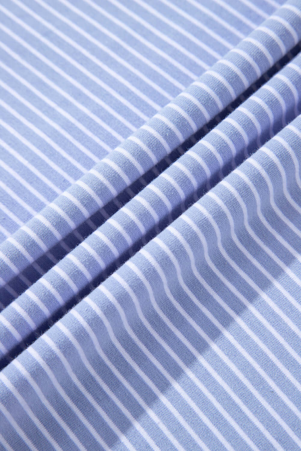 Close-up of sky blue striped fabric, showcasing soft texture and nautical-inspired pattern for stylish apparel.