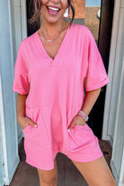 Woman smiling in a soft pink Dreamy Daze romper with short sleeves and deep V-neckline.