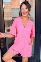 Woman in a pink Dream Daze romper, featuring a deep V-neck and relaxed fit, perfect for casual outings.