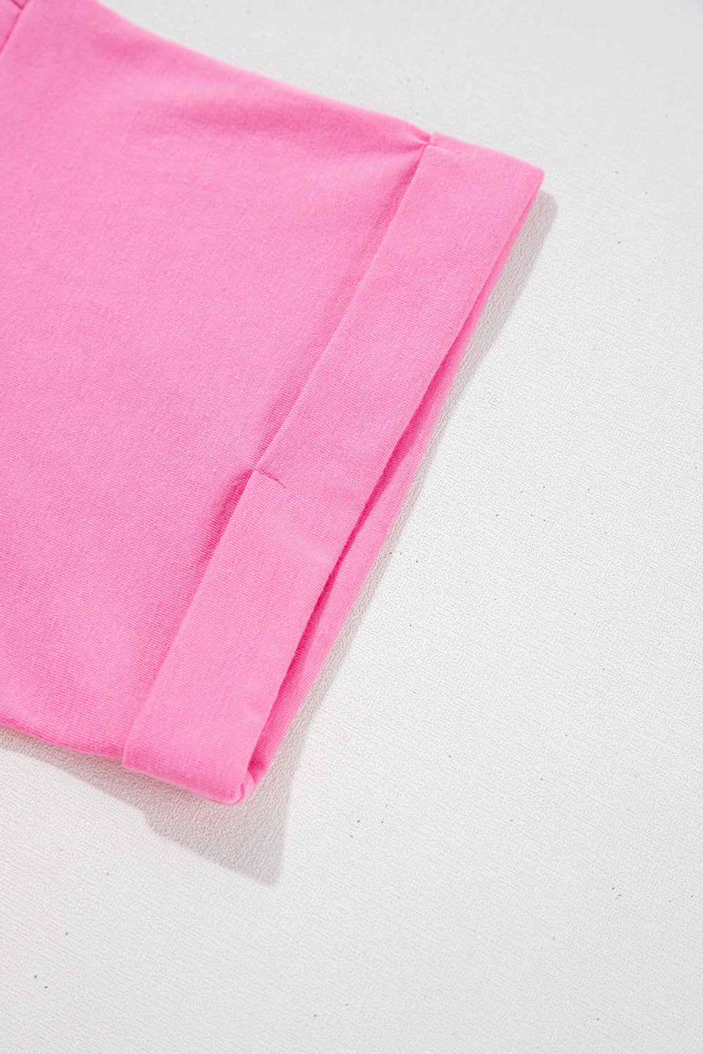 Close-up of the rolled cuff on a soft strawberry pink romper, showcasing its stylish design and vibrant color.