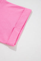 Close-up of the rolled cuff on a soft strawberry pink romper, showcasing its stylish design and vibrant color.