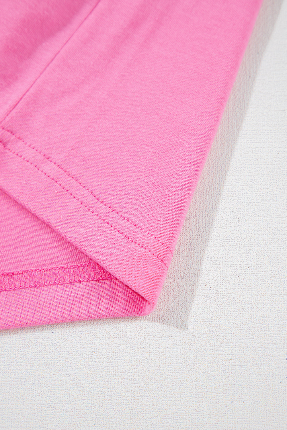 Close-up of the soft, strawberry pink fabric and rolled cuffs of the Dream Daze romper, showcasing its chic style.