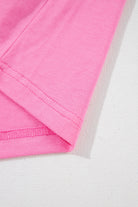 Close-up of the soft, strawberry pink fabric and rolled cuffs of the Dream Daze romper, showcasing its chic style.