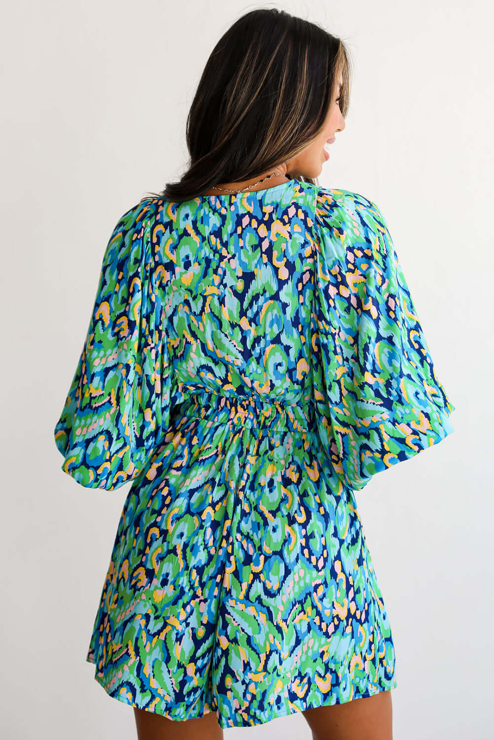 Back view of Wave Dancer Romper in green and blue abstract print with puff sleeves and V-neckline.