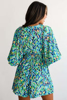 Back view of Wave Dancer Romper in green and blue abstract print with puff sleeves and V-neckline.