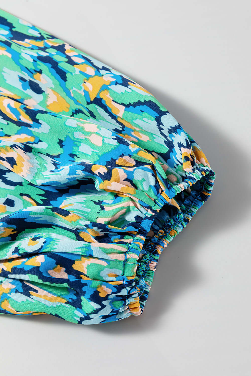 Colorful green and blue abstract print fabric featuring puff sleeve detail from the Wave Dancer Romper.