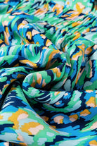 Close-up of vibrant green and blue abstract print fabric, showcasing a flowing and playful design for summer fashion.