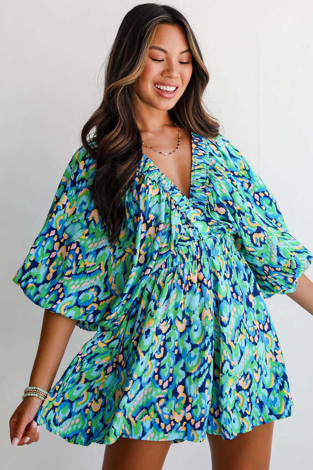 Woman in green and blue abstract print puff sleeve romper, showcasing playful summer style.