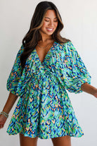 Model in green and blue abstract print Wave Dancer Romper with puff sleeves and V-neckline, perfect for summer.