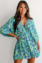 Woman in green and blue abstract print Wave Dancer Romper with puff sleeves and V-neckline, showcasing summer style.