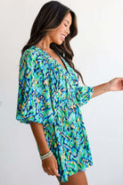 Model wearing the Wave Dancer Romper in a vibrant green and blue abstract print, showcasing a flattering V-neckline and puff sleeves.