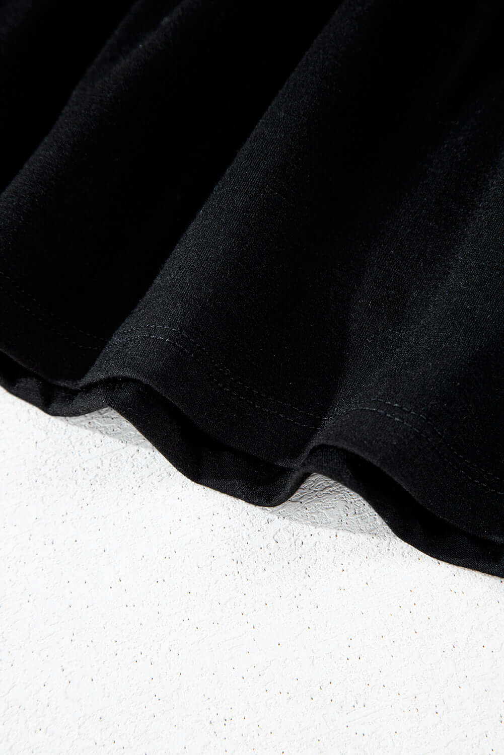 Detail of Eclipse Edge Skort showing the black fabric and ruched hem for a sleek activewear look.