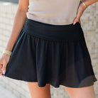 Model wearing the Eclipse Edge Skort with a sleek black wide waistband, showcasing stylish ruching and built-in shorts.