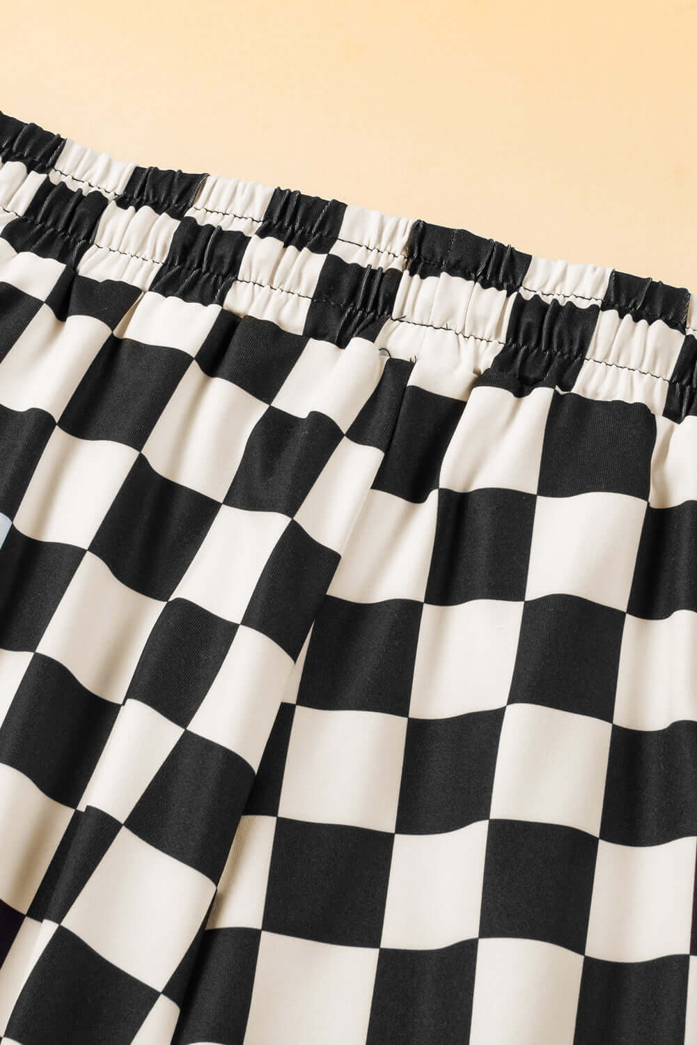 Close-up of black and white checkered drawstring shorts waistband for a stylish and casual look.