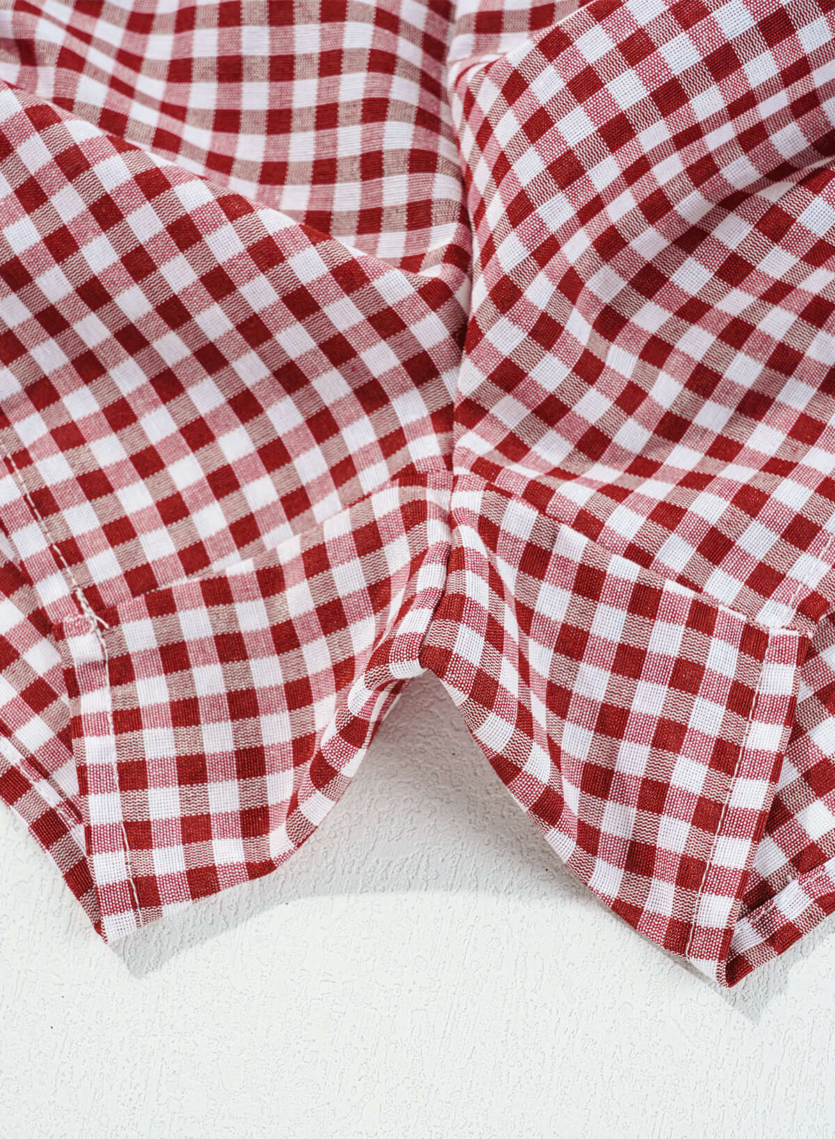 Red gingham fabric close-up for Picnic Perfect Shorts, showcasing high waist style and comfort.
