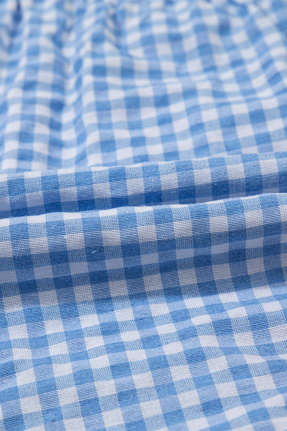 Close-up of blue gingham fabric showing details of the Picnic Perfect Shorts, emphasizing texture and pattern.