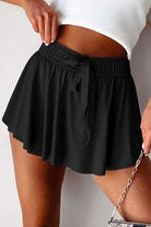 High-waisted black skort with stretchy waistband, perfect for sporty style and casual wear.