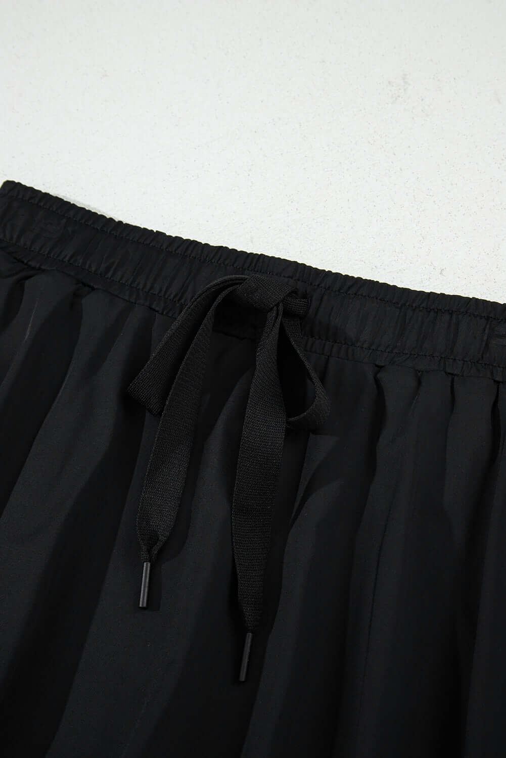 Close-up of the high-waisted drawstring waistband on a black skort, showcasing its sporty and stylish design.