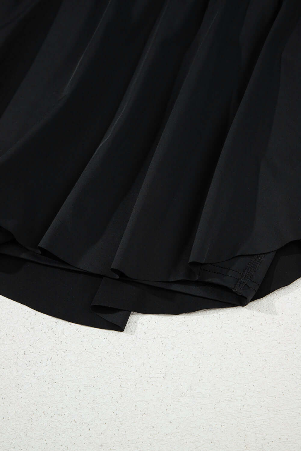 Close-up of the Twilight Tempo Skort showcasing its flowy black fabric and layered design for sporty elegance.