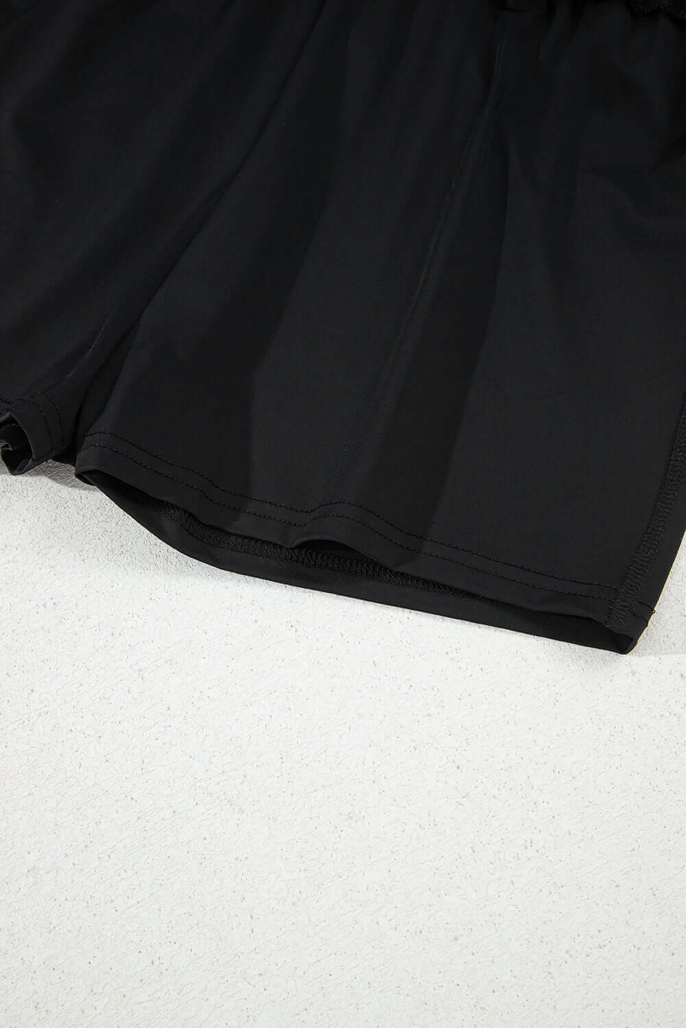 Close-up of black high-waisted skort showing built-in shorts and stretchy waistband for comfort.