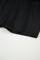 Close-up of black high-waisted skort showing built-in shorts and stretchy waistband for comfort.