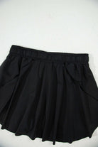 High-waisted black skort with stretchy waistband and flowy overlay for sporty and stylish looks.