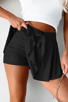 High-waisted black skort featuring a drawstring waistband and flowy overlay for sporty and stylish looks.