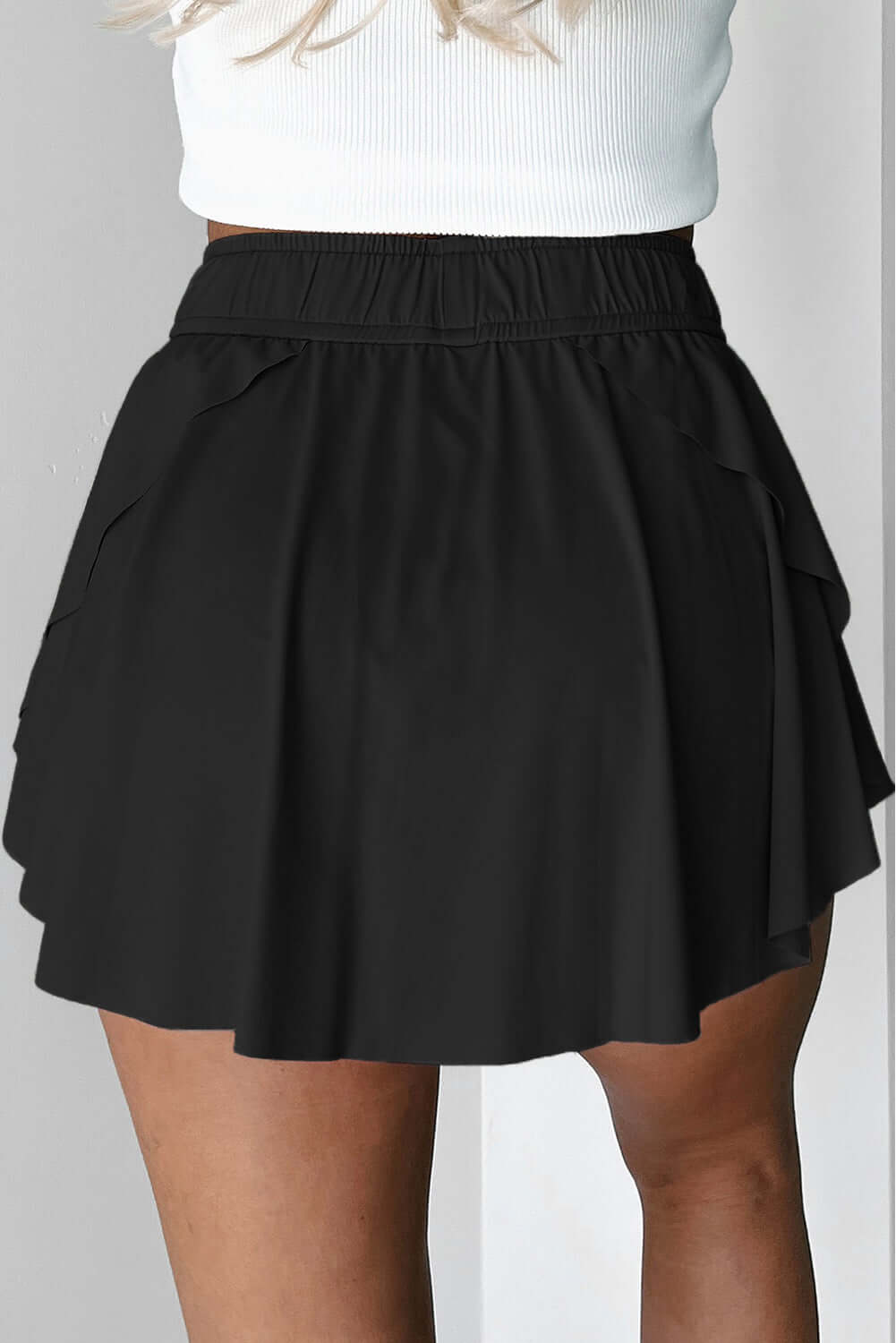 Flattering black twilight tempo skort with a stretchy waistband and flowy overlay, perfect for sport and casual wear.