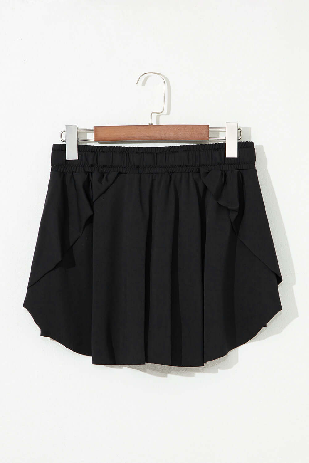 Black high-waisted skort with drawstring waistband and flowy overlay, perfect for sporty and casual looks.