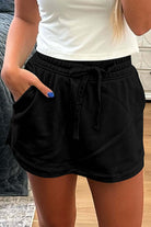 Black French terry skort featuring a drawstring waist and side pockets for casual comfort.