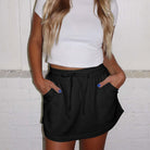 Woman modeling a black drawstring skort, showcasing casual style with pockets and comfort.