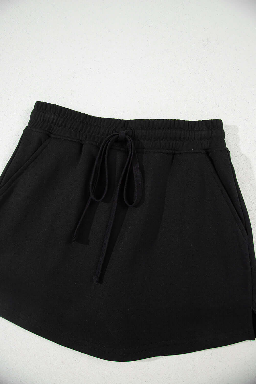 Black French terry drawstring skort with pockets and adjustable waist for casual comfort.