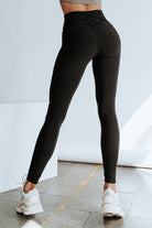 Black high-waisted leggings with crisscross detail for gym or daily wear, offering tummy control and a flattering fit.