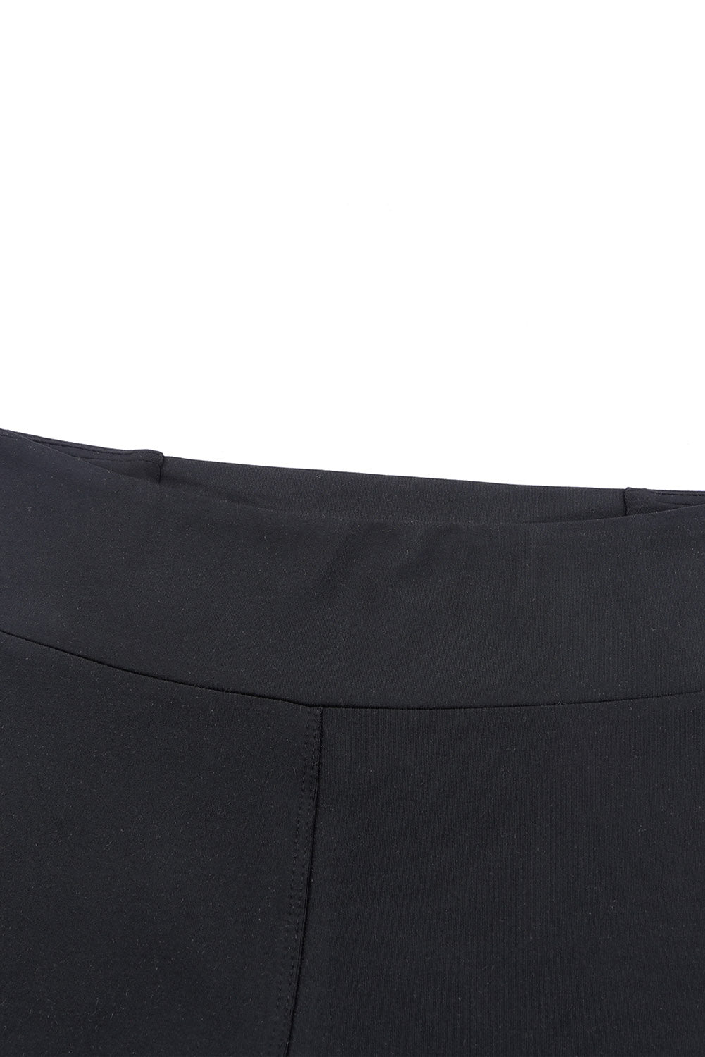 Close-up of high-waisted black leggings showing tummy control detail and crisscross design.