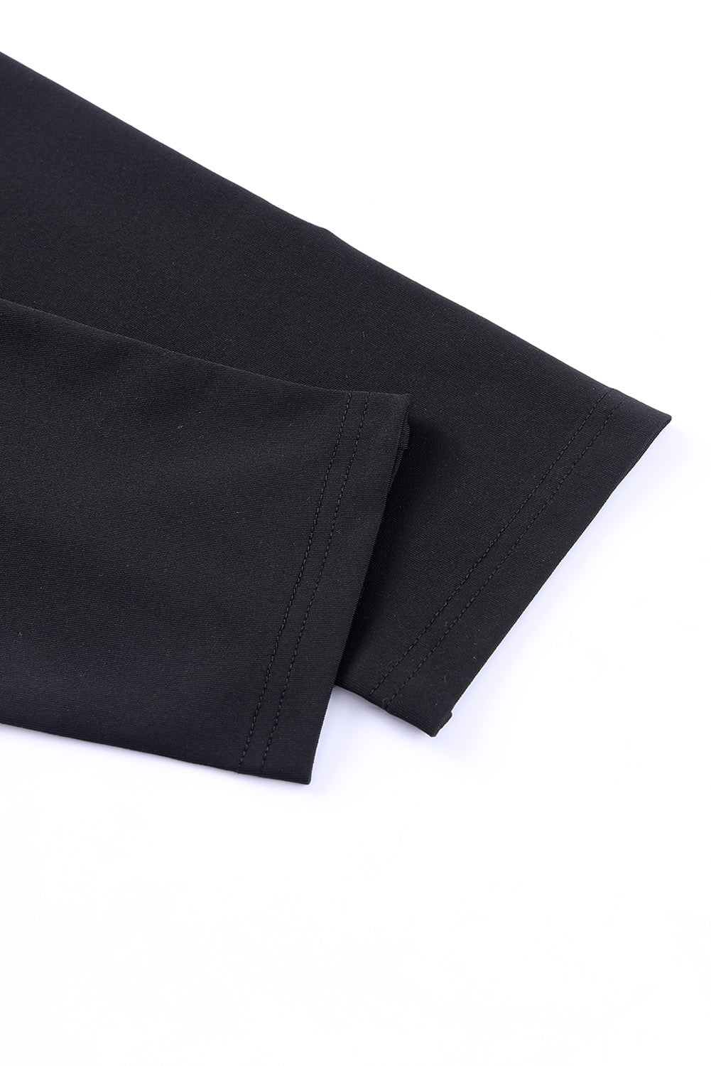 Close-up of the sleek black fabric of Crossed Paths leggings, showcasing their high-waisted and stretchy design.