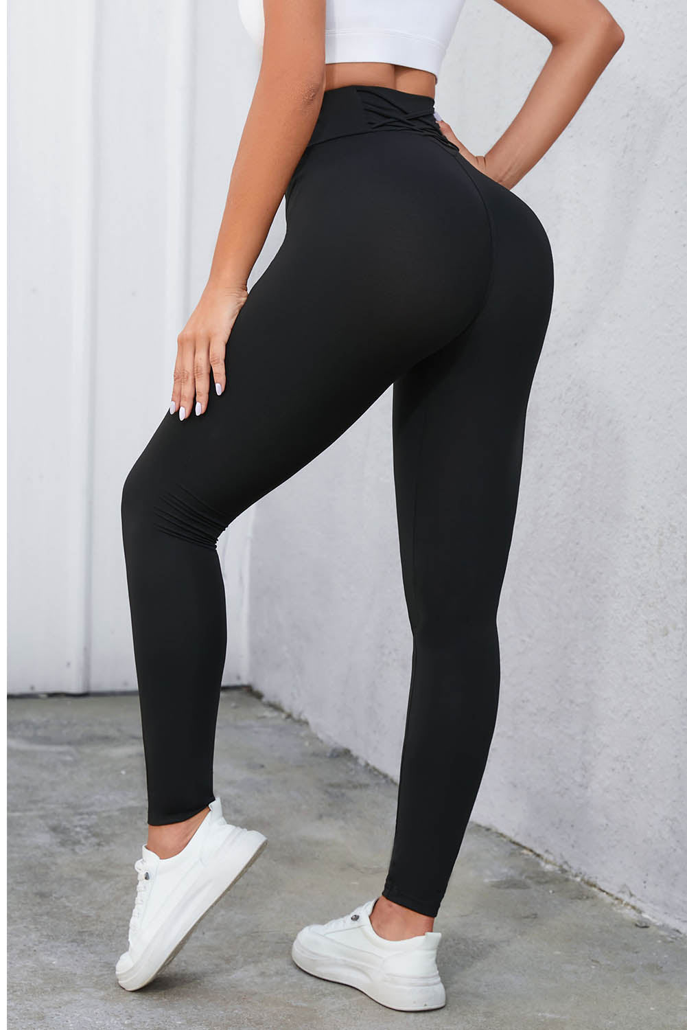 High-waisted black leggings with stylish crisscross details, perfect for gym and everyday wear.