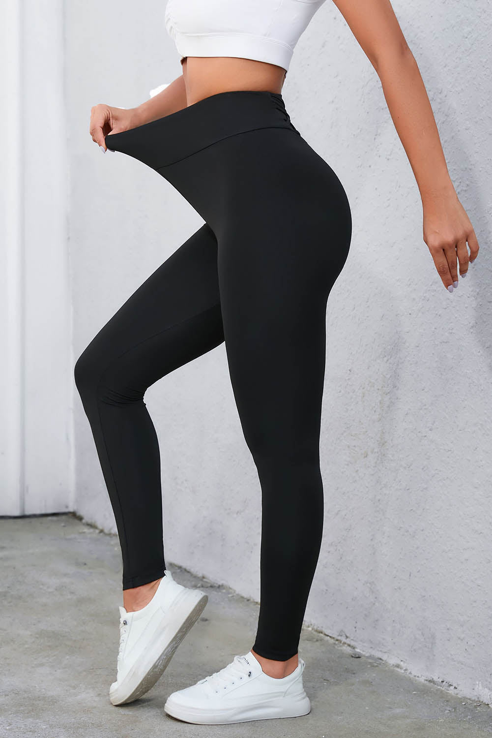 High-waisted black leggings with crisscross detail, ideal for workouts and stylish casual wear.