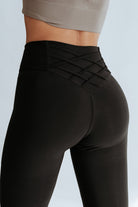 High-waisted black leggings with crisscross detail for tummy control and flattering fit, perfect for gym and daily wear.