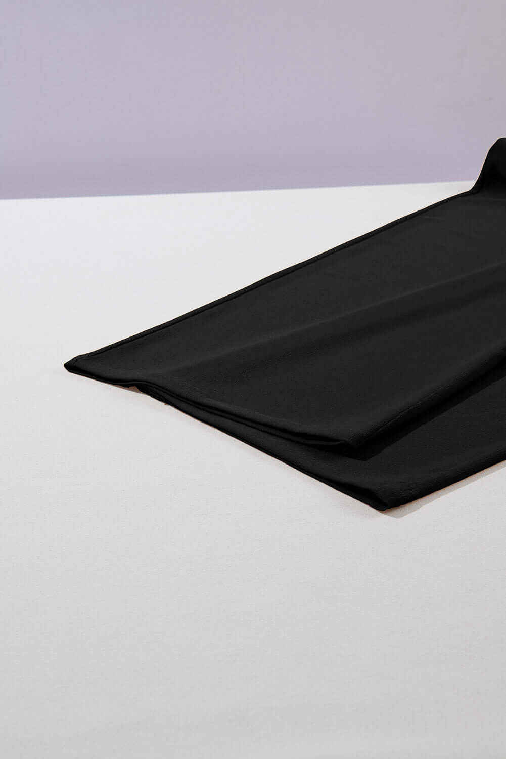 Black fabric draped on a flat surface, showcasing its soft, flowy texture for stylish pants.