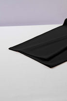 Black fabric draped on a flat surface, showcasing its soft, flowy texture for stylish pants.