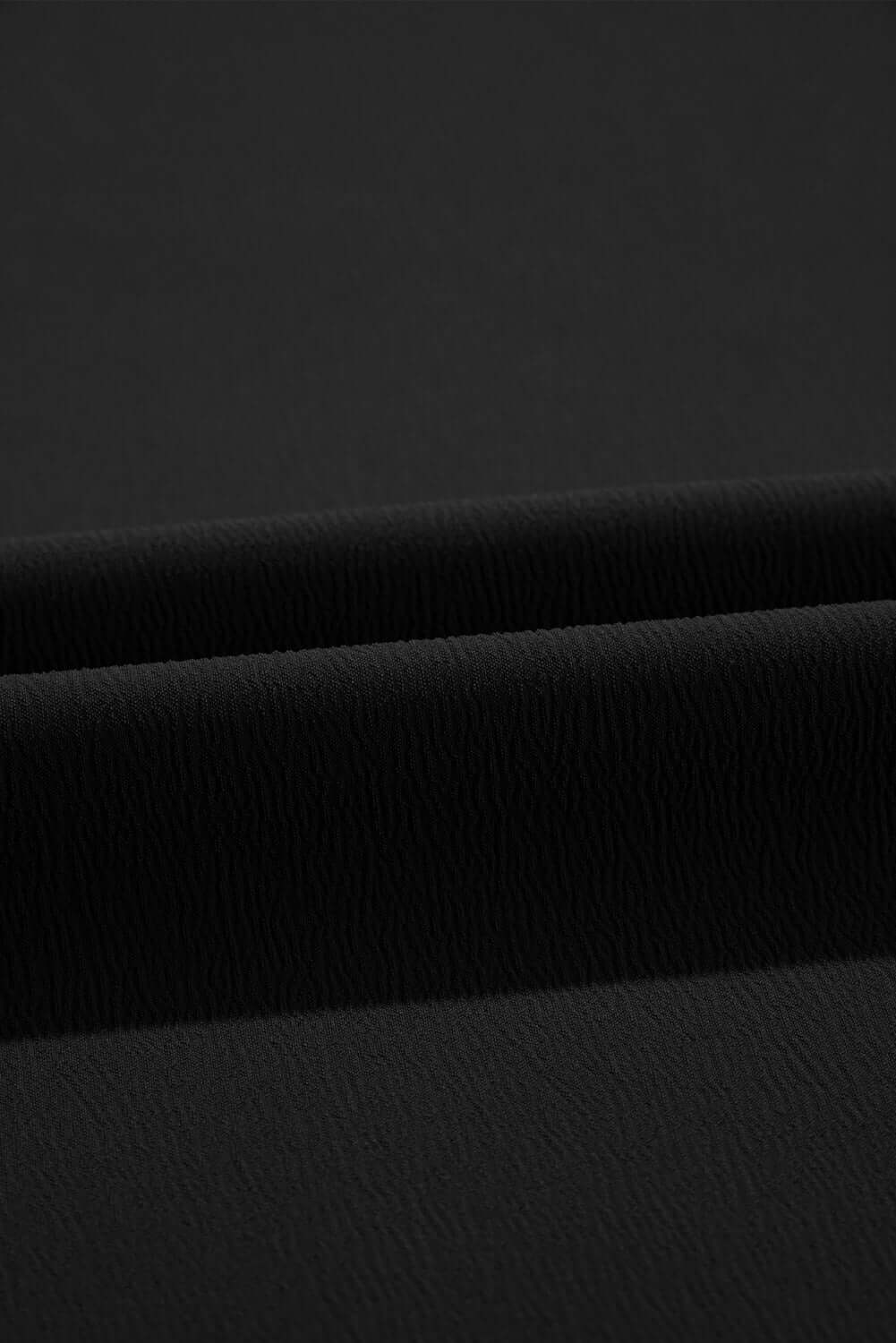 Close-up of soft black fabric texture, showcasing a smooth, flowy material ideal for wide leg pants.
